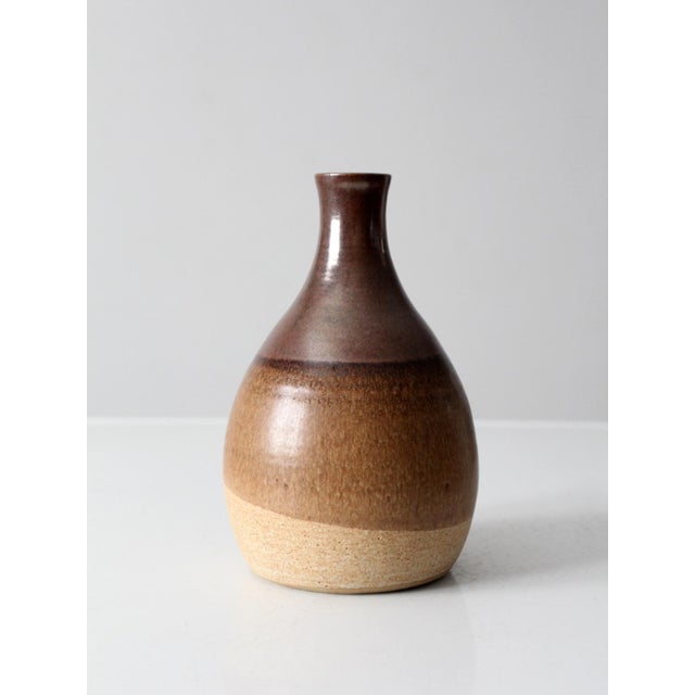 This vintage studio pottery decanter vase features a beautifully layered brown and tan glaze over sturdy stoneware. Its...