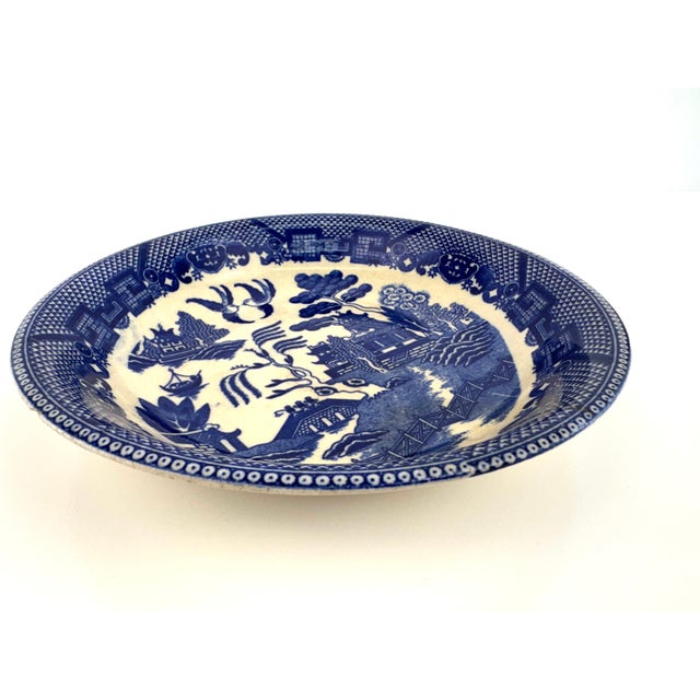 Antique blue and white transferware bowl featuring a detailed chinoiserie landscape with pagodas, trees, and birds. The...