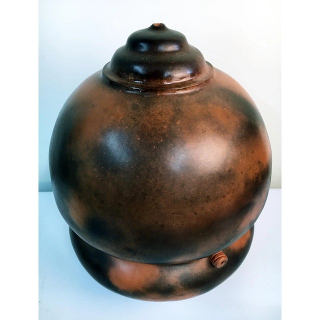 This 14" traditionally pit-fired raku ceramic seed vase has a velvety earth-tone finish. One of three available from a...