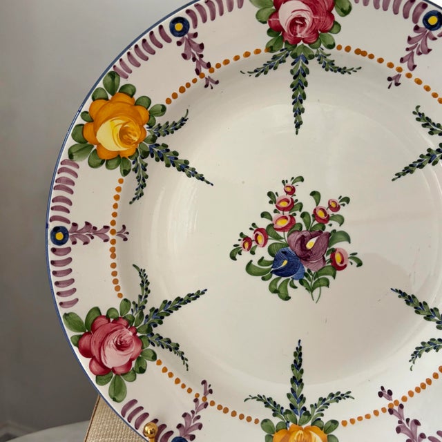 A vintage hand-painted floral faience wall plate, made by Zell. Features raspberry pink, orange, and indigo flowers with...