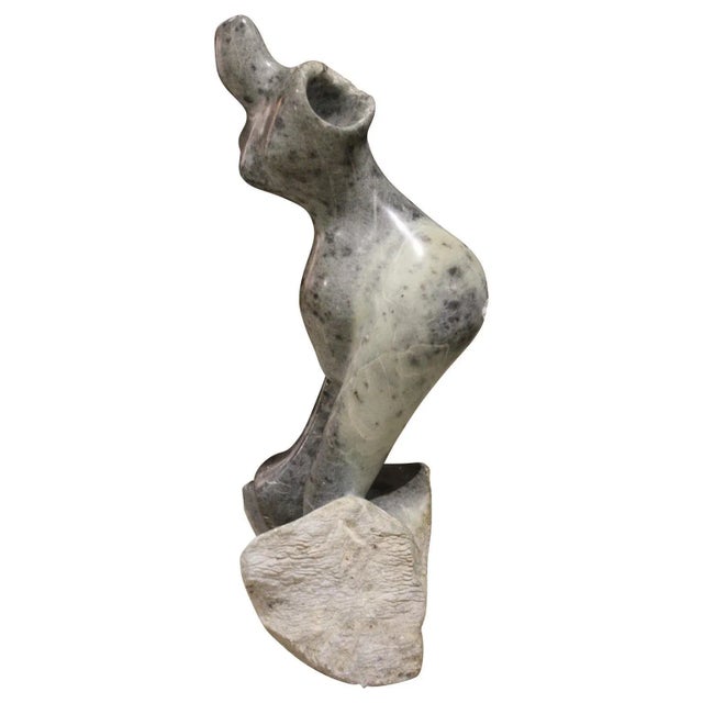 Figurative sculpture of a nude female figure. The stone is a grey tone with speckling. The artist signed and dated the...
