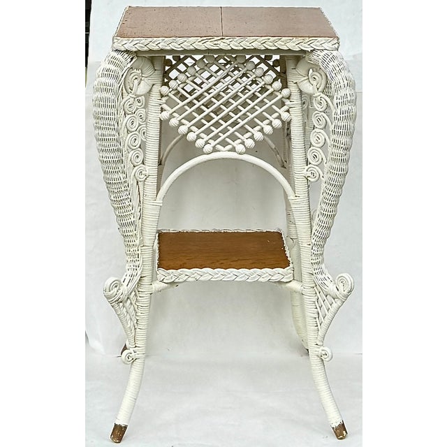 A sculptural antique Victorian era wicker table with ornate scrollwork and a two-tier design – perfect as a plant stand,...