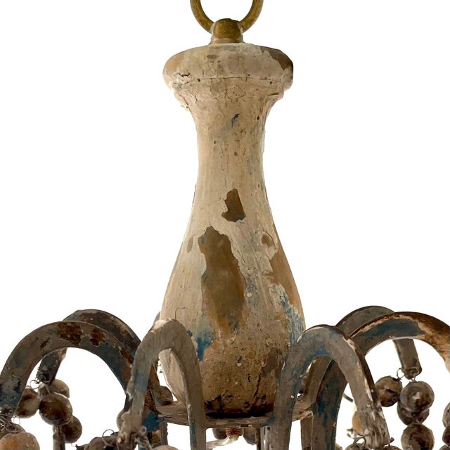 Antique French eight arm chandelier. Iron frame hung with patinated wooden beads, pendants, and candle holders. Beeswax...
