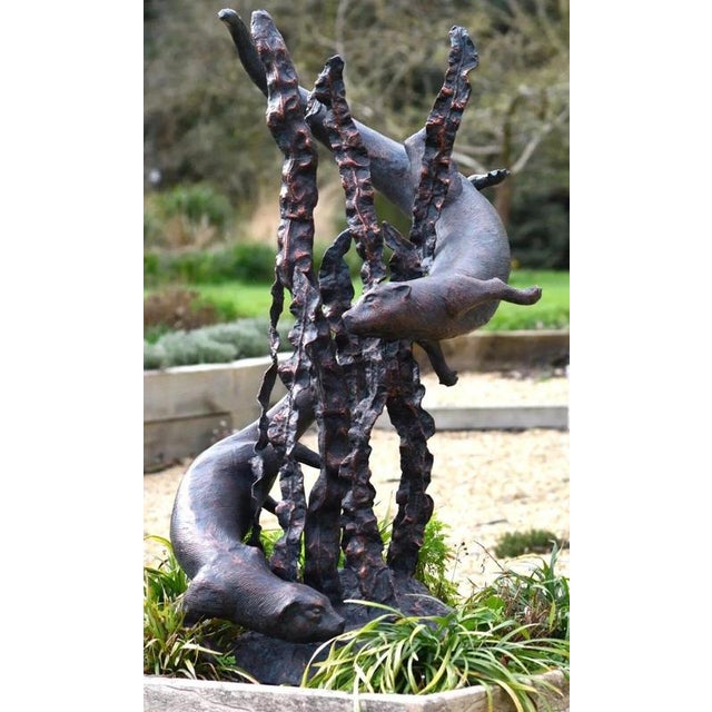 A spectacular large-scale garden fountain sculpture depicting two playful otters swimming amongst tall, sculptural strands...
