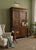 A beautifully contoured, projecting top surmounts two large paneled doors, flanked by turned half-columns on the sides....
