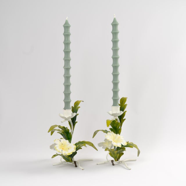 A pair of vintage Italian tole metal candlestick holders featuring delicate hand-painted off-white and pale yellow flowers...