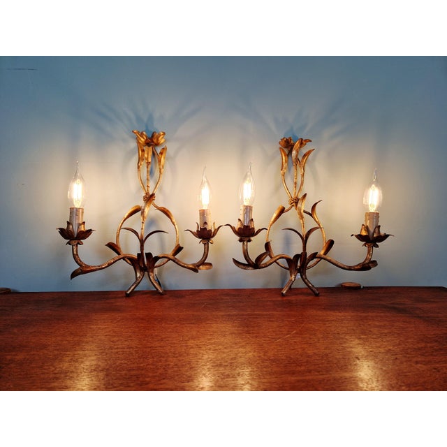 Pair of floral wall sconces in gold-tone metal, produced in Italy in the 1960s. Each sconce has two light points...