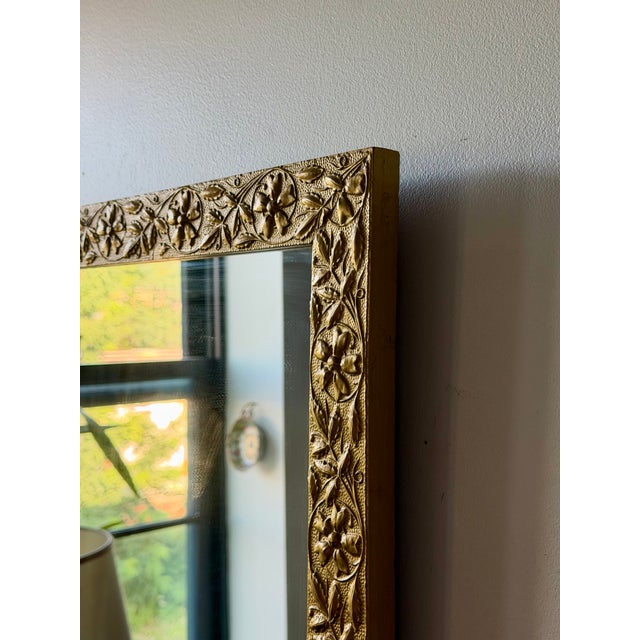 Early 20th-century giltwood wall mirror featuring an embossed floral motif and richly textured gold finish. A beautiful...