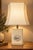 A chinoiserie-style table lamp, likely dating from the 1970s. The rectangular, chamfered base is made of beige composite...
