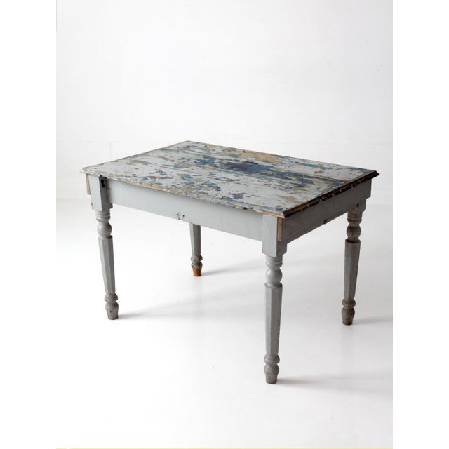 Antique farmhouse work table with a substantial plank top, turned and tapered legs, and layers of beautifully worn blue...