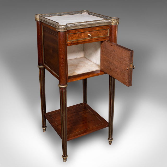 This is an antique bedside table. A French, walnut, marble and inlaid brass nightstand, dating to the early Victorian...