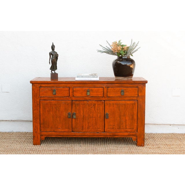 This vintage Asian sideboard, painted in a warm rust orange hue, exudes a rustic elegance and a touch of global flair. The...