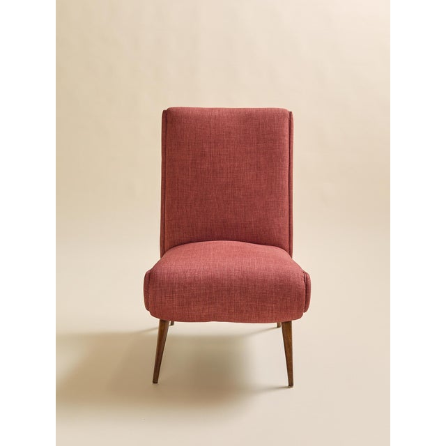 These vintage slipper chairs features a high upholstered back, rounded seat, and slim tapered wood legs. The rust-toned...