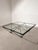 Striking postmodern coffee table - Paolo Piva , featuring a clear glass top supported by an architectural black metal...