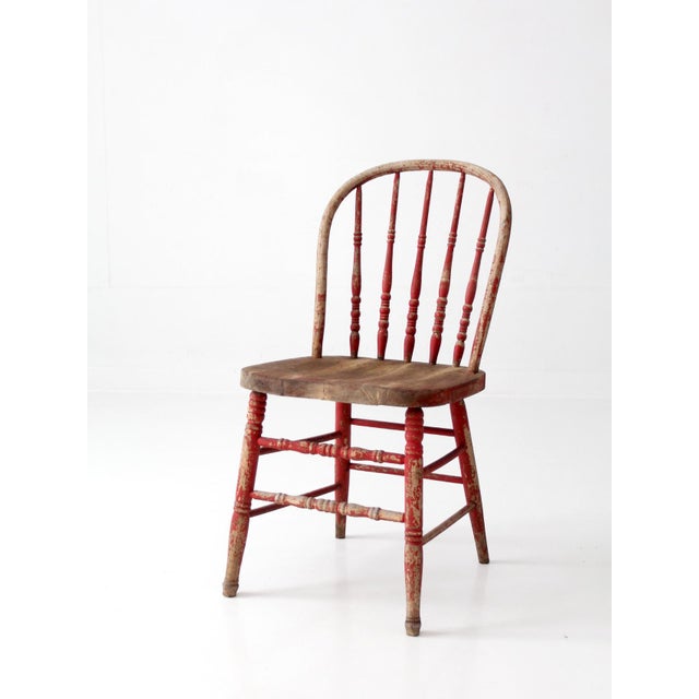This antique Windsor spindle-back chair features a beautifully aged red finish, a natural wood seat, and distinctive...