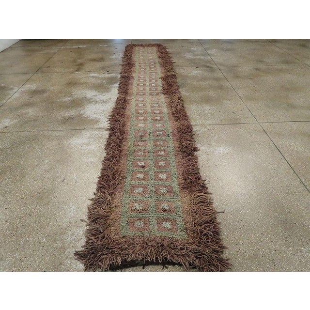 A vintage Tibetan rug in runner format handmade during the mid-20th century. Measures: 2' 6" x 16' 1".