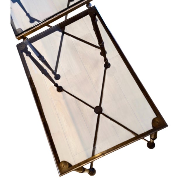 On offer are a pair of midcentury, Maison Jansen-inspired patinated solid brass side tables with smokey glass tops....