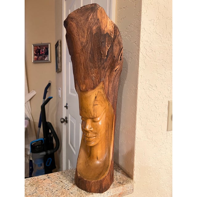 This is a remarkably detailed wood sculpture by a talented wood artist. The human face, either male or female, seems to be...