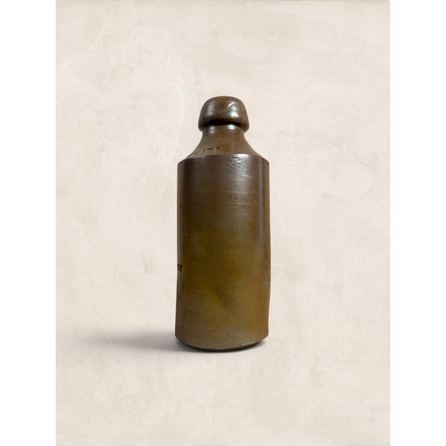 An antique English stoneware ginger beer bottle by R. White, dating to circa 1900. Finished in a rich brown salt-glazed...