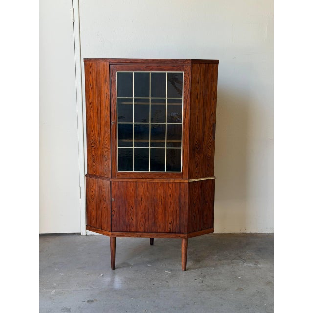 Mid Century Modern Danish corner cabinet crafted in richly grained rosewood, featuring dramatic natural figuring and warm...