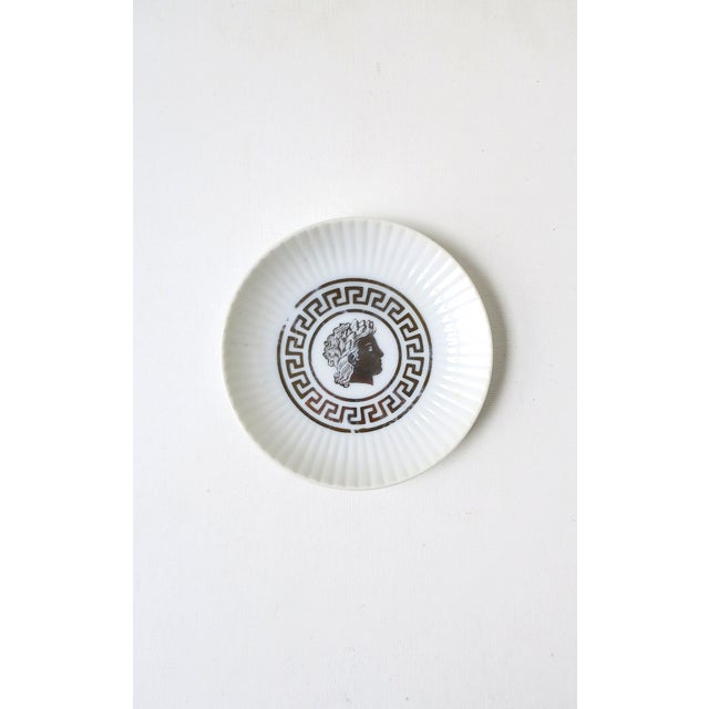 A fluted white porcelain dish with male head/bust center surrounded by a Greek-Key design, in the Greco-Roman style, circa...