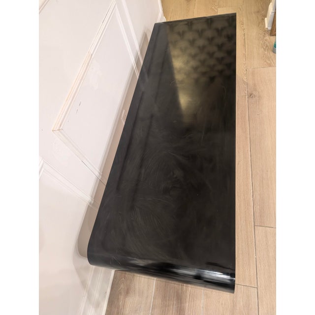 Striking Karl Springer–style waterfall coffee table featuring a sculptural, continuous curved form in black formica. This...
