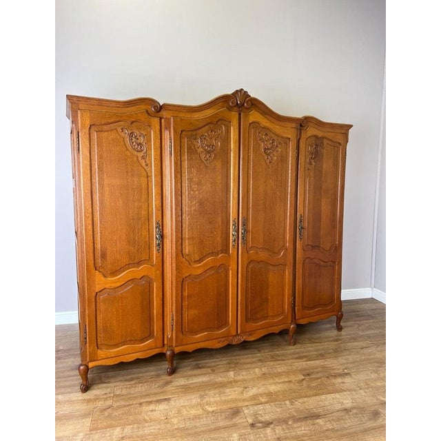 A beautifully presented Vintage French Louis wardrobe in oak, featuring four shaped panelled doors decorated with elegant...