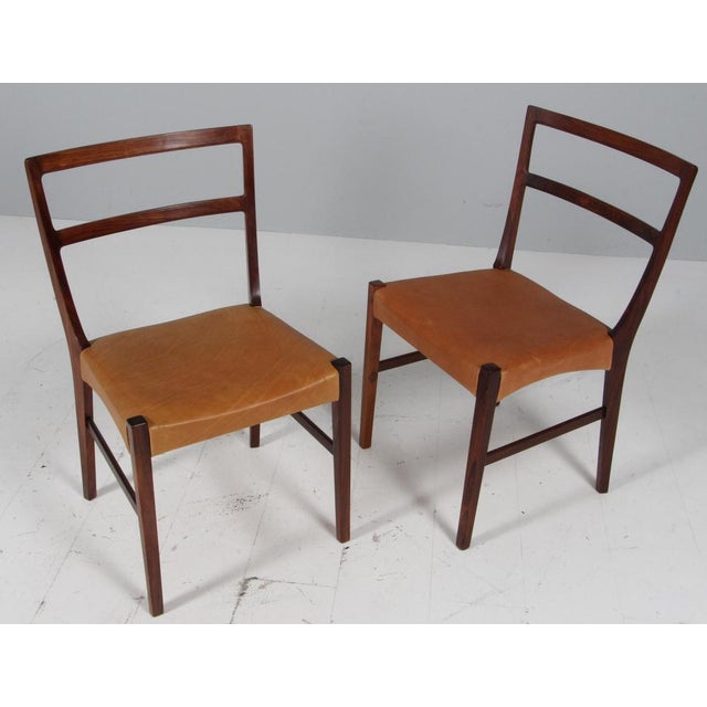 Johannes Andersen two dining chairs in solid oiled rosewood. New upholstered with vintage tan aniline leather. Made by...