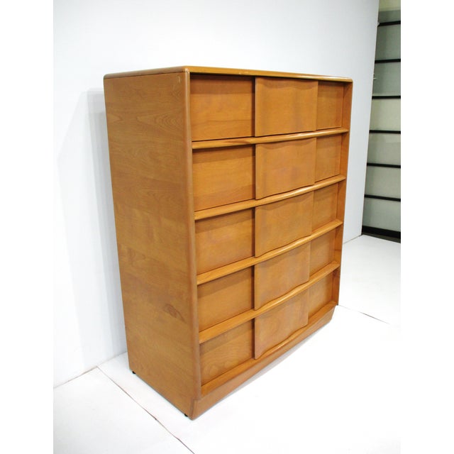 A five-drawer high boy dresser in the champagne finish model number M792 with the fronts having a wavy design motif and...