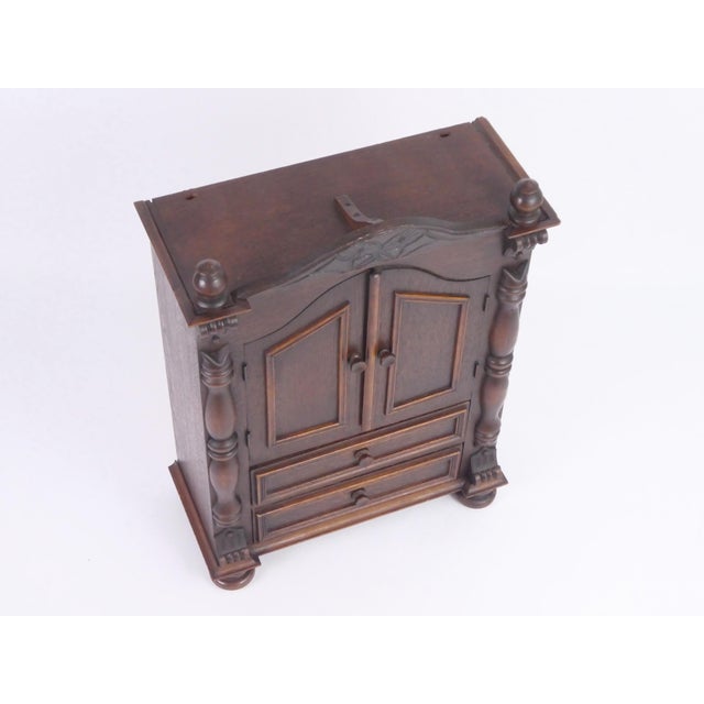 A vintage wooden cabinet with two drawers and two doors. It is crafted from solid wood and finished in a rich, dark brown...