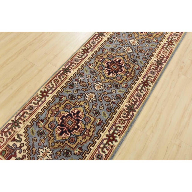A traditional tribal Heriz runner hand-knotted with an all-wool pile on a cotton foundation. This oriental rug features...