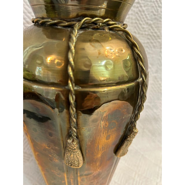 This hammered brass urn shaped vase has all the extras. The neck is “tied” with brass rope and tassel trim. The body is...