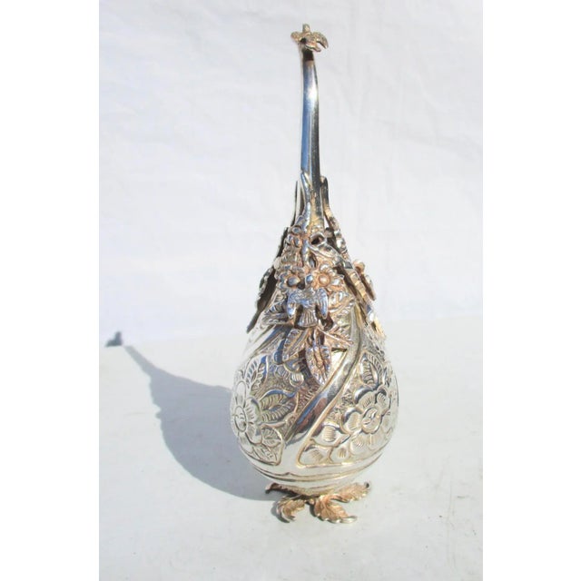 Sprinkler for rose water with engraved and repousse body and cast spout and feet. Screw on top with cast foliage and...