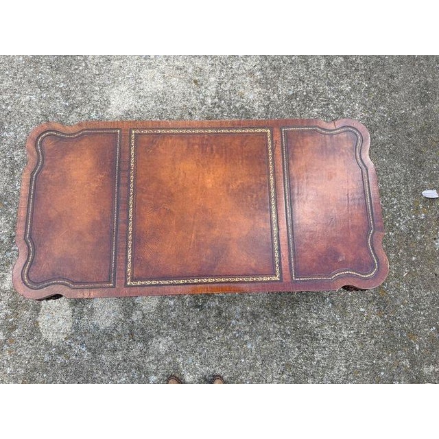 Great sized coffee table featuring curved corners and ball and claw feet. Top showcases three panels of embossed leather,...