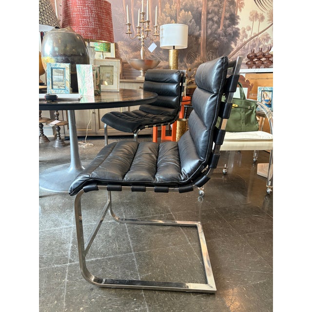 Restoration Hardware black leather Oviedo Dining Chairs featuring a stainless steel frame and channel tufted cushions....
