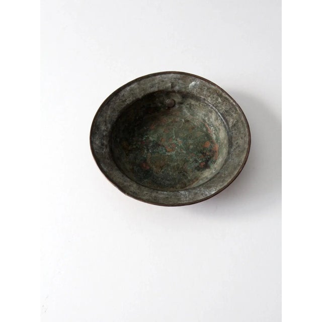 This is an antique copper pan. The shallow hammered copper basin features a brass ring for hanging storage.