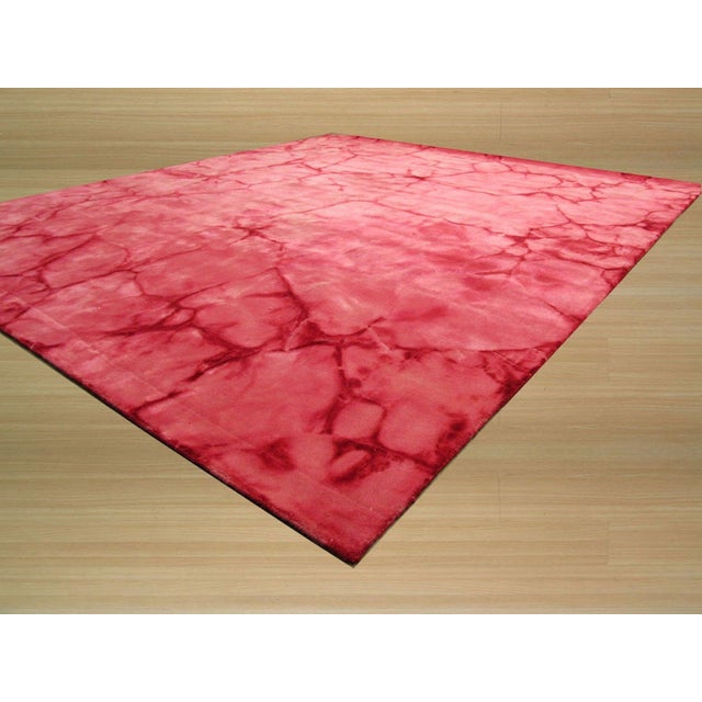 A 5' x 8' hand-knotted wool rug with a coral pink abstract with a deeper red marbled veining. Newly made in India. Size:...