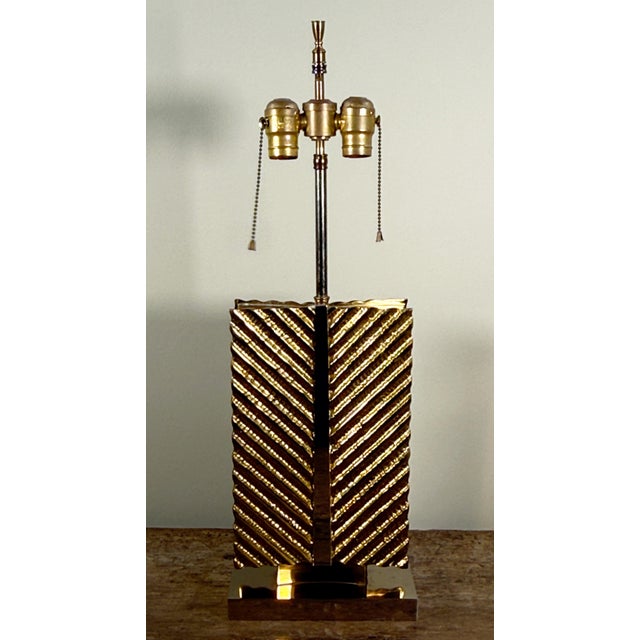 This table lamp by Maison Baguès features a rectangular brass body with diagonal striped texturing creating a chevron...