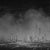 This artwork presents a monochromatic cityscape, where towering structures emerge from a dark, atmospheric background. The...