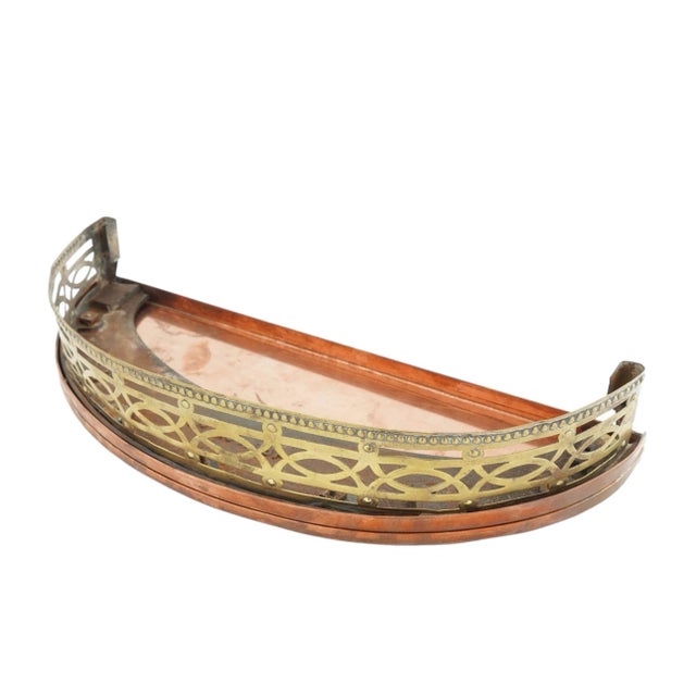 A diminutively scaled late Georgian fire fender of pierced sheet brass over a cast iron frame with a copper tray base. The...