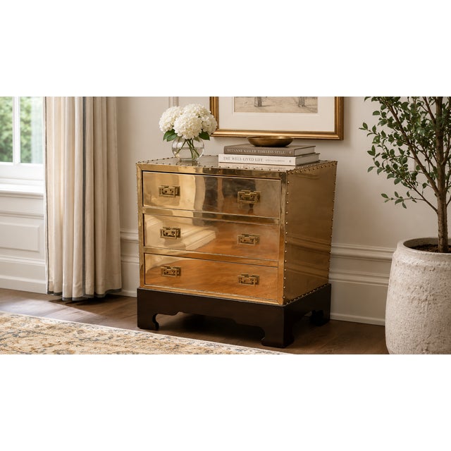 This brass-clad three-drawer chest is attributed to Sarreid Ltd. and reflects the company’s signature campaign-inspired...