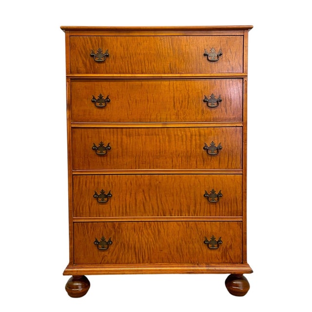 Vintage five-drawer chest featuring a warm-toned finish with prominent figured wood grain across the drawer fronts. The...