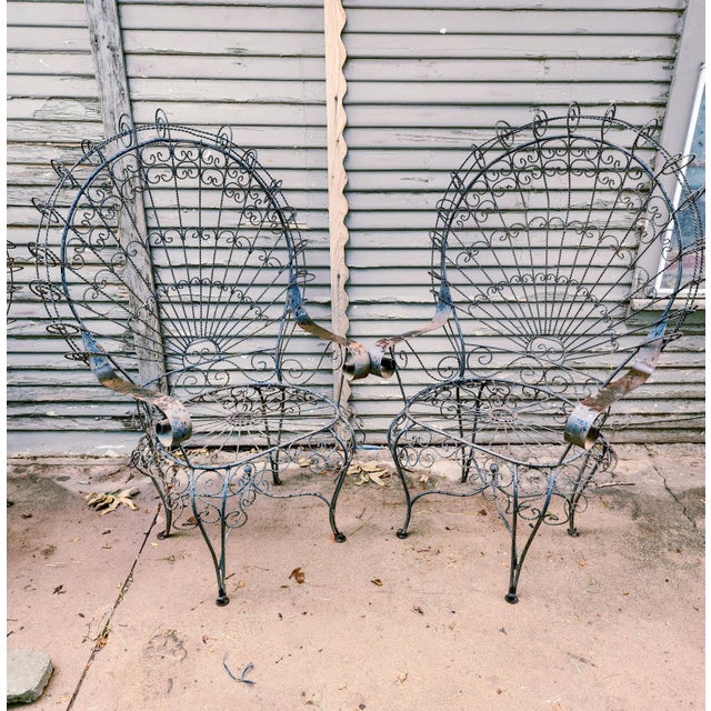 Offered for your consideration is a highly coveted, matched pair of vintage wrought iron peacock chairs, masterfully...