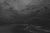 Shores of Next Year features a dramatic seascape rendered in a monochromatic palette, where swirling clouds dominate the...