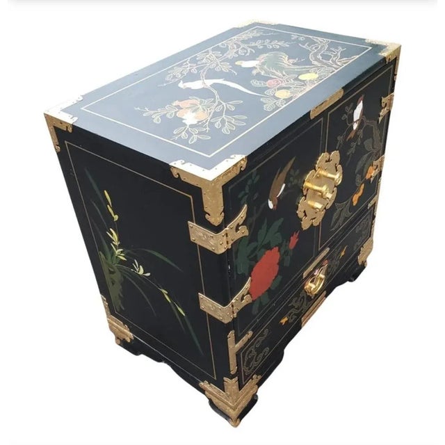 Small black lacquered chinoiserie cabinet features hand painted motif of birds and flowers on the top and sides and brass...