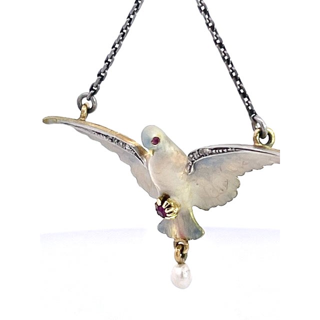 This exquisite antique necklace features a spread-winged dove rendered in luminous white and cream enamel, suspended...