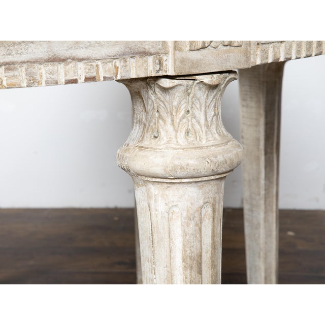 A pair of French Neoclassical style painted wood demilune console tables from the late 19th century, with carved rosettes,...