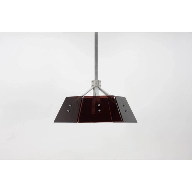 This 1970s pendant light is comprised of robust industrial aluminum hardware and brown acrylic glass panels. European Plug...