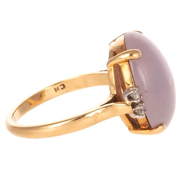 14K yellow gold ring featuring an Oval Cabochon Lavender Jade measuring approximately 15.8 x 12.2 mm. The softly...