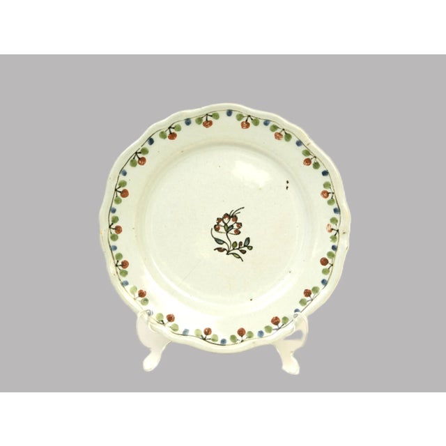 Hand-painted brown and green berries on vine surrounding a scalloped rim of this in-glazed, deep-welled, faience plate...